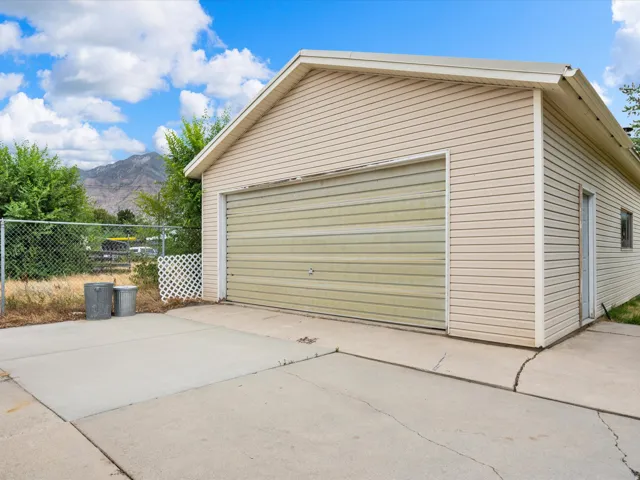 Detached garage featuring horizontal siding, a single garage door, and an adjacent service door