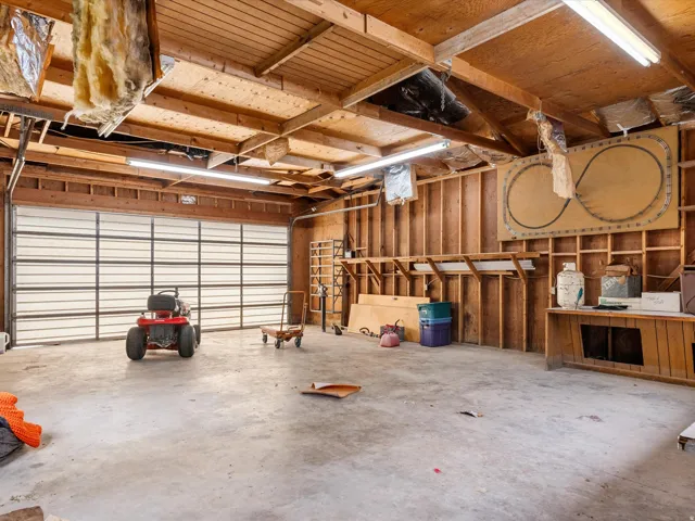Spacious garage featuring a concrete floor, exposed wood beam ceiling, and a large rollup door