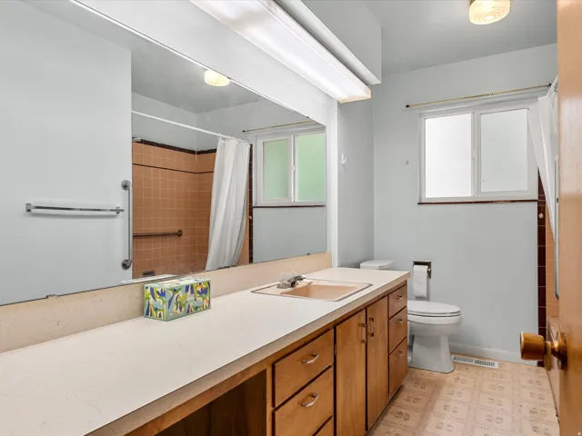 Bathroom featuring a wood-finish vanity with a built-in sink and a large mirror