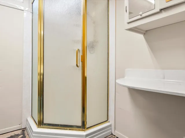 Corner shower enclosure featuring frosted glass panels and gold-tone framing