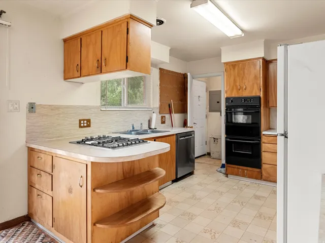 Kitchen featuring wood cabinetry, a gas cooktop, double wall ovens, a dishwasher, and patterned floor tile