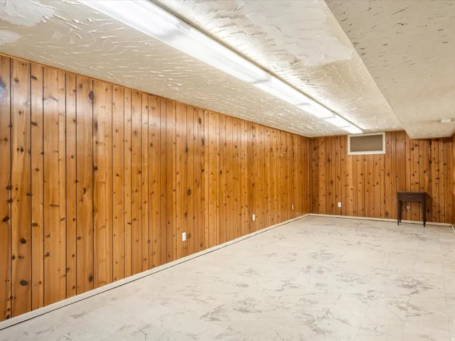 Spacious room featuring wood paneling on walls