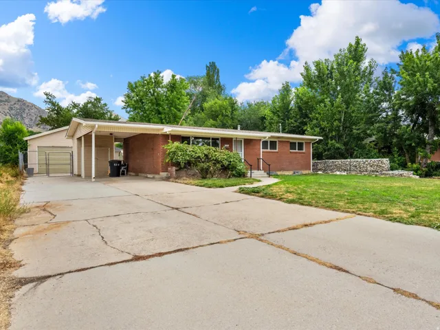 Brick exterior home with an attached carport and a separate detached garage structure
