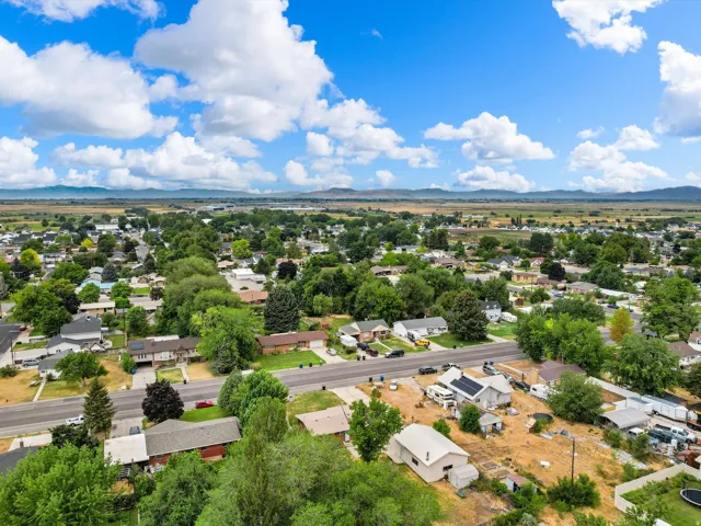 Residential neighborhood featuring mature trees, paved roadways, and distant mountain ranges
