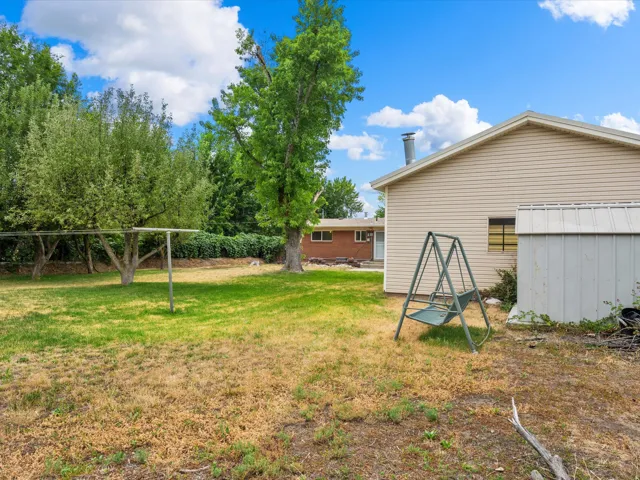 Expansive rear yard featuring mature trees and a clothesline