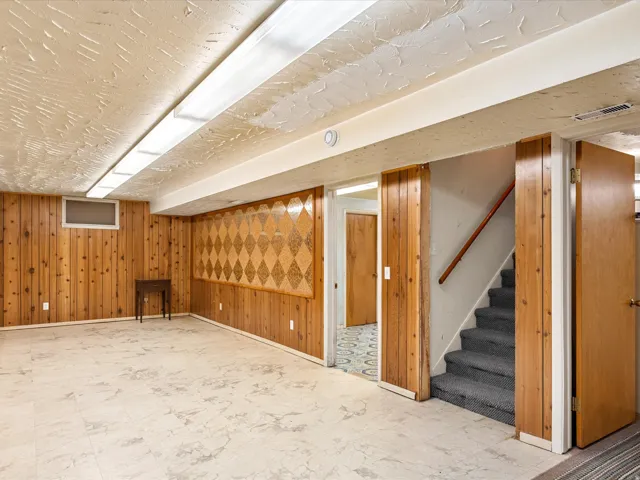 Spacious room featuring wood paneling, decorative wall accents, and light-colored flooring