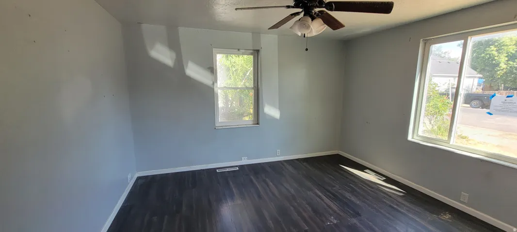 Spacious room featuring dark wood-finish flooring, light gray walls, and white trim