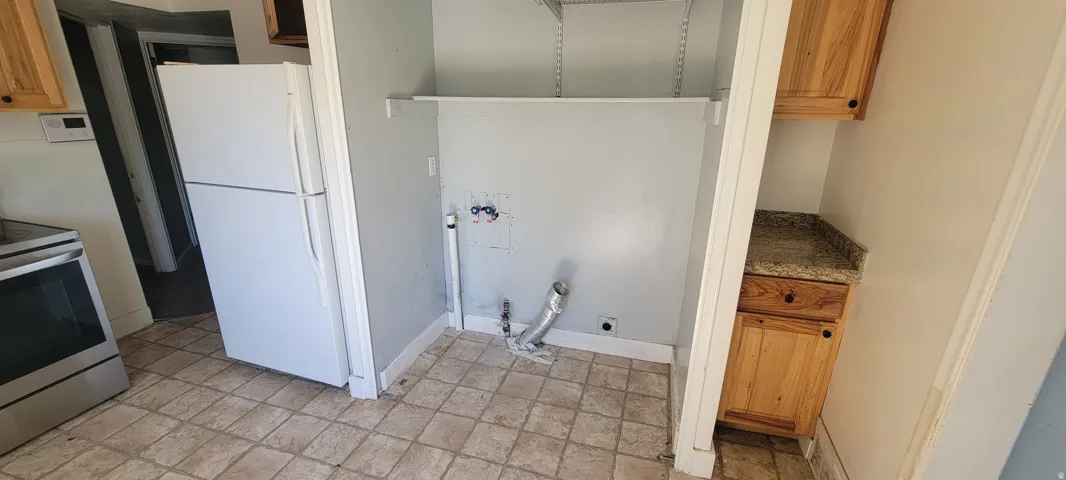 Dedicated utility space featuring hookups and shelving for laundry appliances