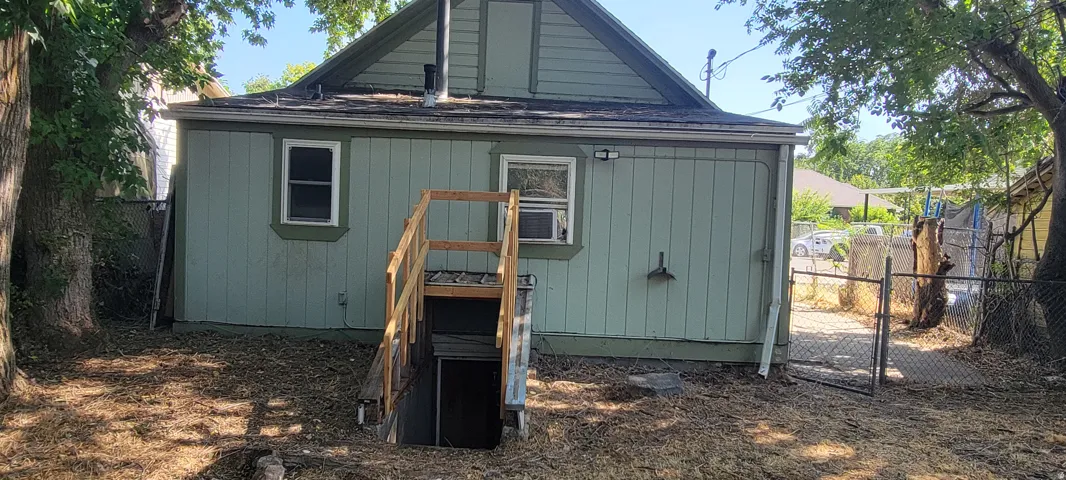 Rear exterior featuring a basement entry with wood handrails, horizontal panel siding, and a gabled roofline