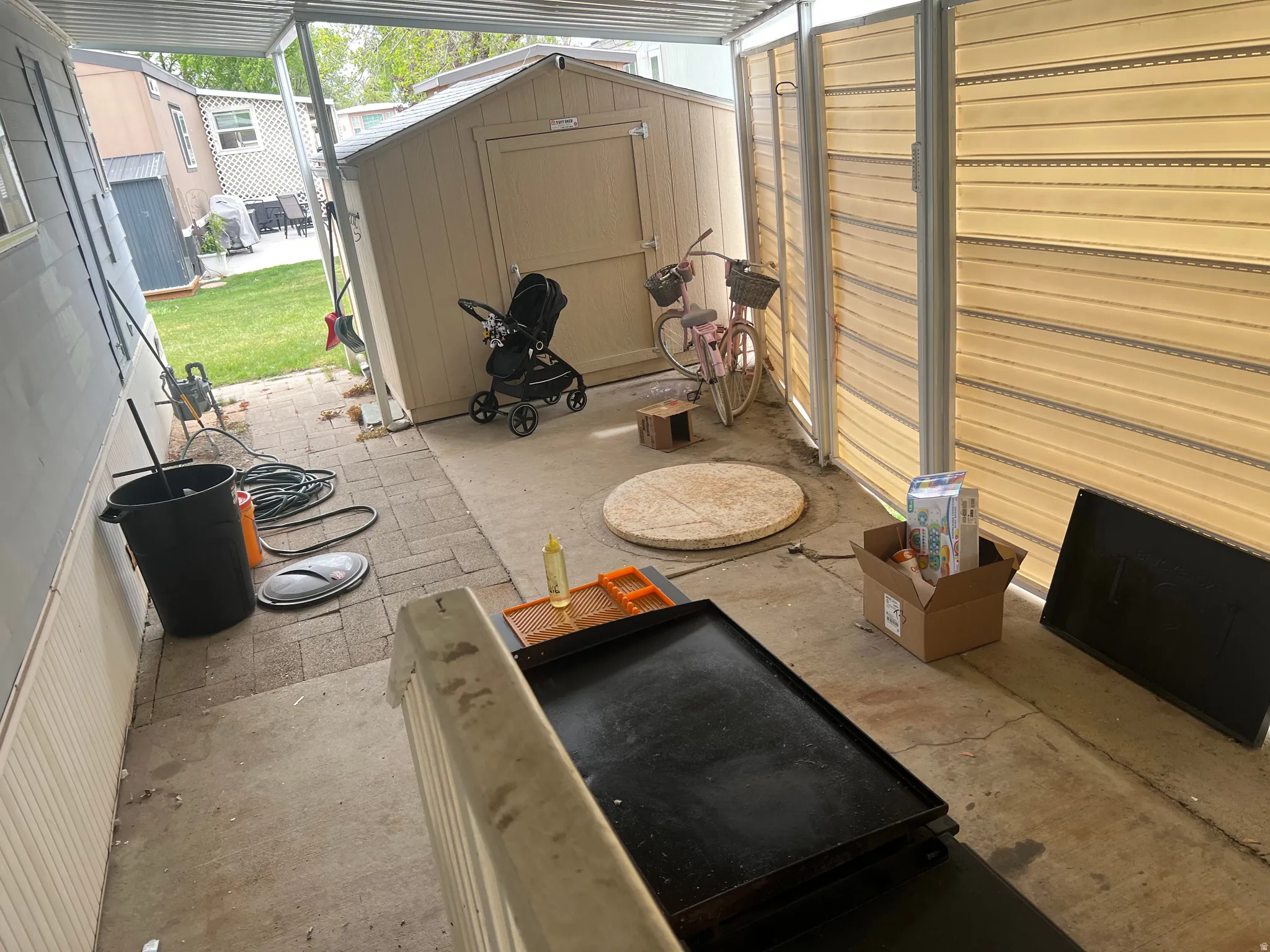 Covered patio area featuring concrete flooring and a partial paver walkway