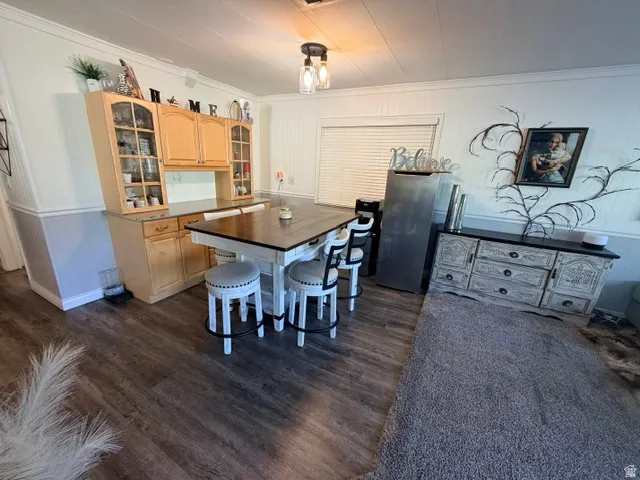 Open-concept dining area featuring wood-finish flooring, two-tone wall paneling, and a contemporary ceiling light fixture