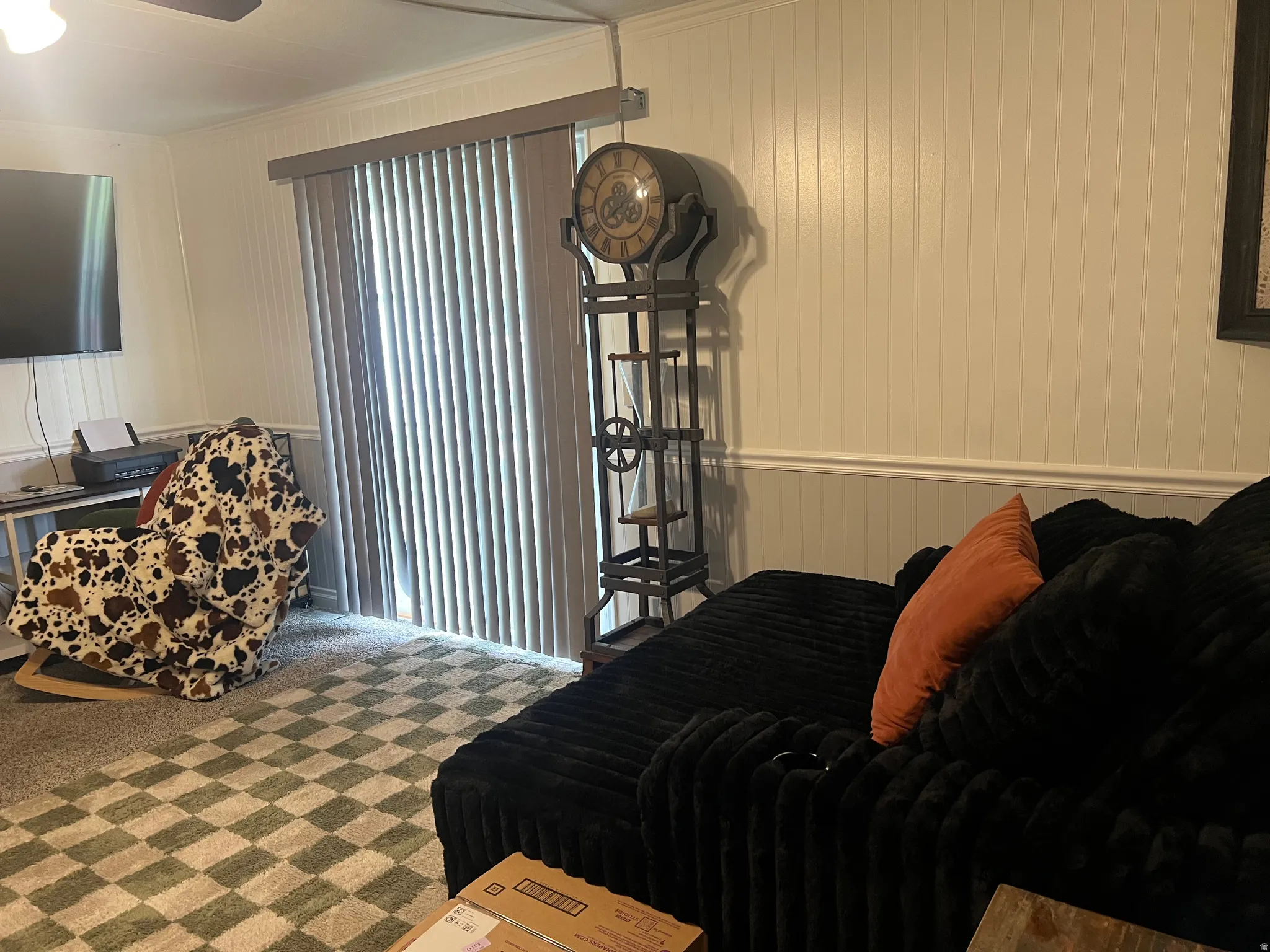 Room featuring vertical blinds on a sliding glass door, beadboard wall paneling, crown molding, and a ceiling fan