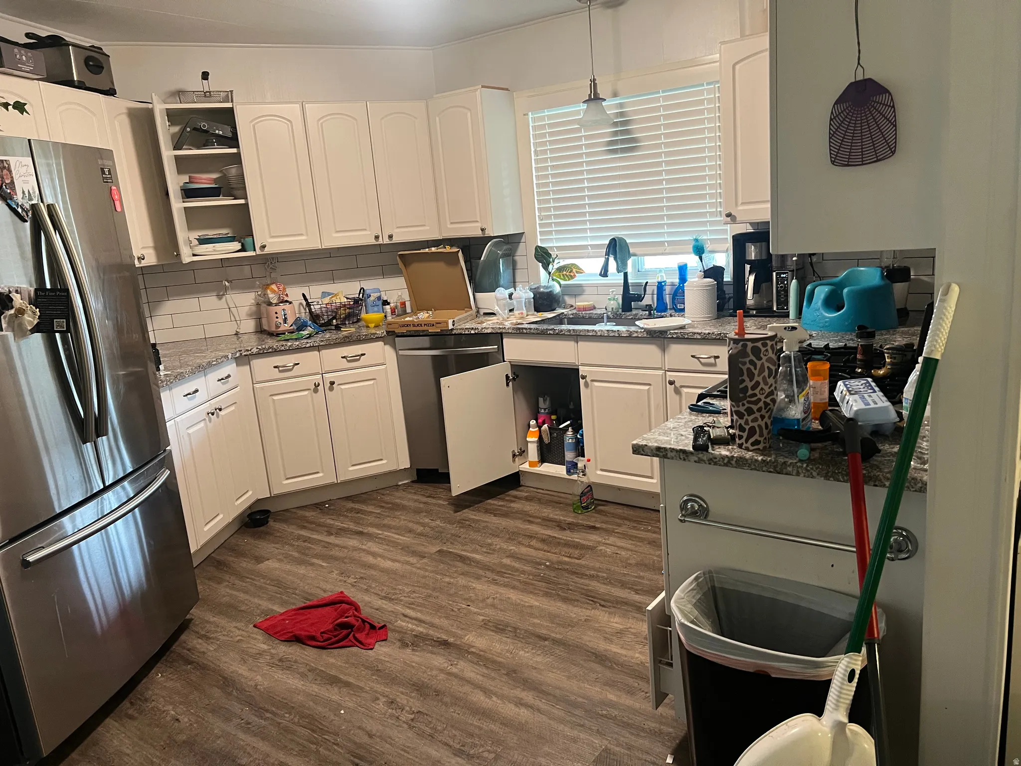 Kitchen featuring wood-finish flooring, white cabinetry, granite-style countertops, and a subway tile backsplash