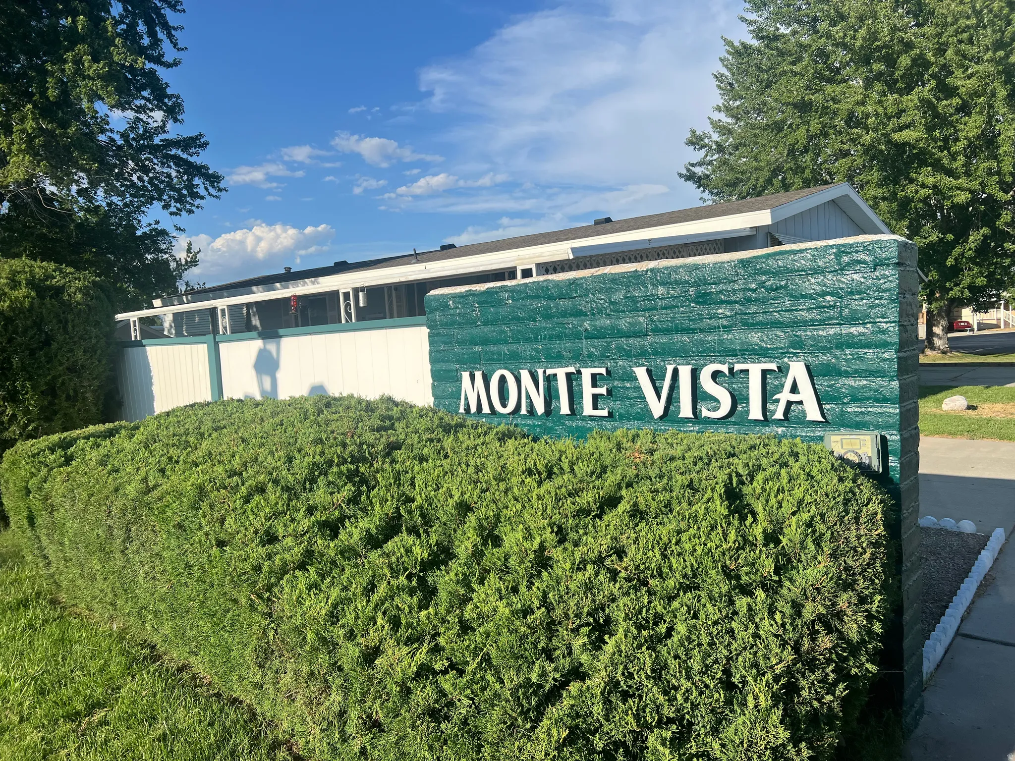 Entry monument featuring "MONTE VISTA" lettering, surrounded by manicured shrubbery and green lawn