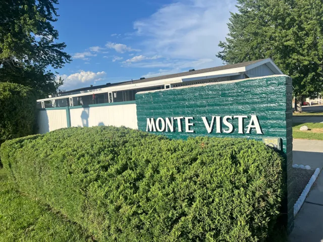 Entry monument featuring "MONTE VISTA" lettering, surrounded by manicured shrubbery and green lawn