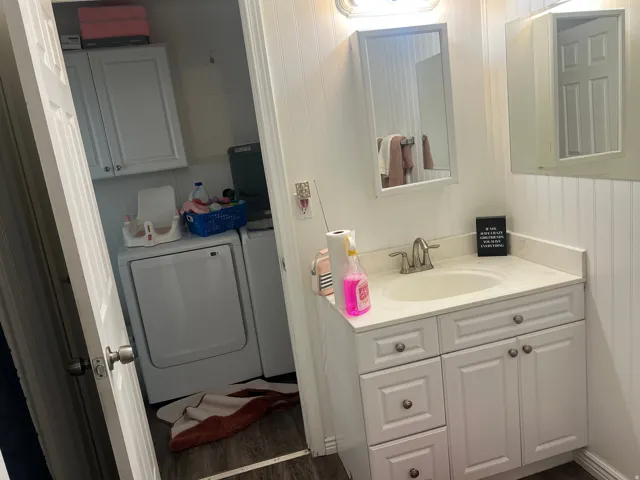 Vanity with a single basin sink, brushed nickel faucet, and white shaker-style cabinetry. Door to Laundry Room