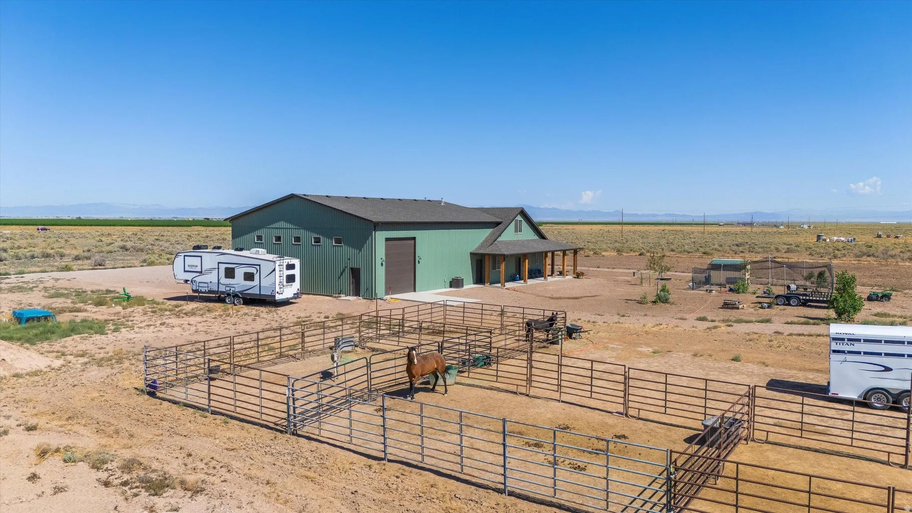 Expansive property featuring a large green barn structure with multiple windows and a covered porch with wooden columns