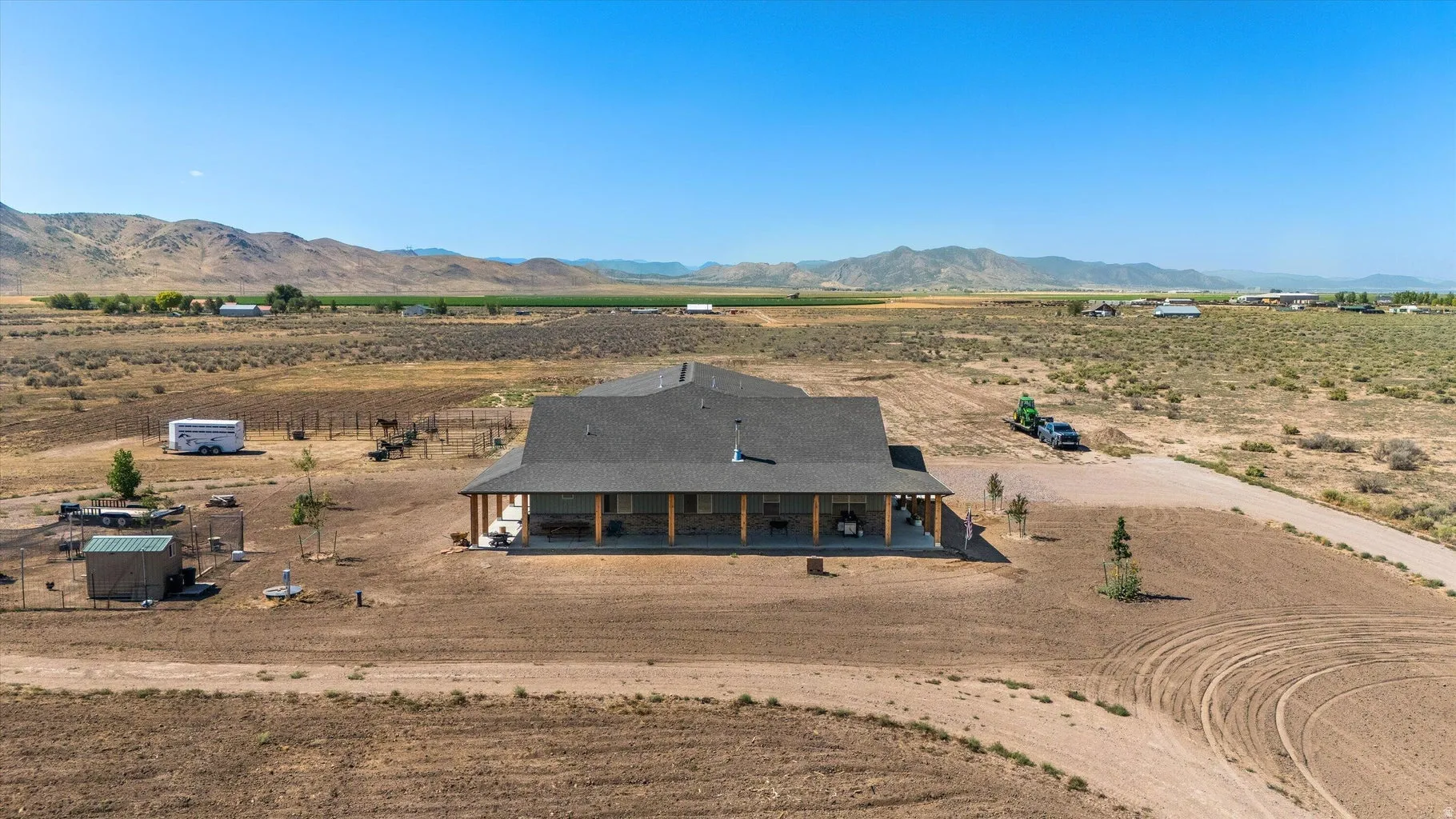 Ranch-style residence featuring a dark shingle roof and a spacious covered porch with exposed wood beams