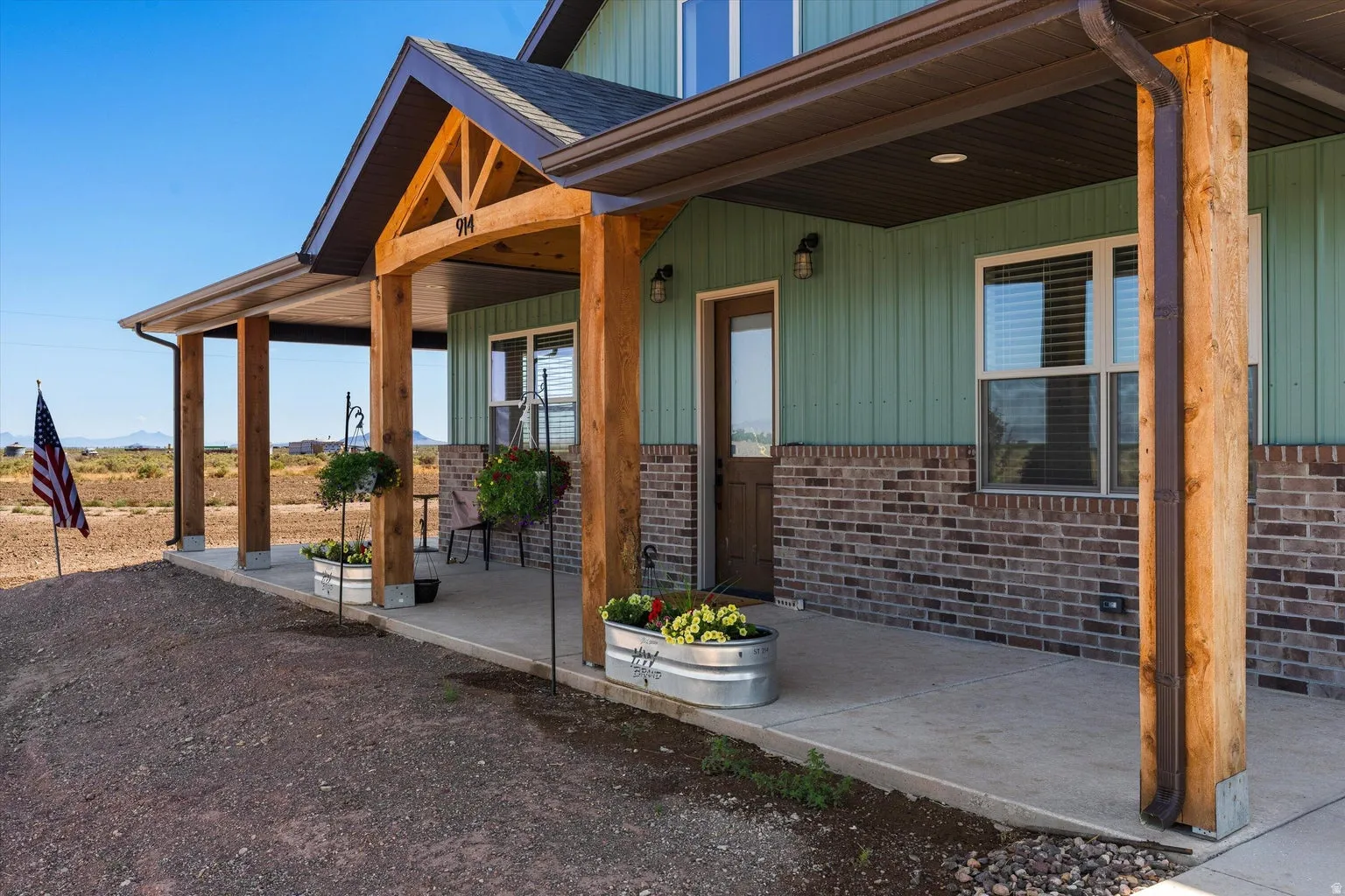 Covered front porch featuring rustic wood columns and a concrete surface