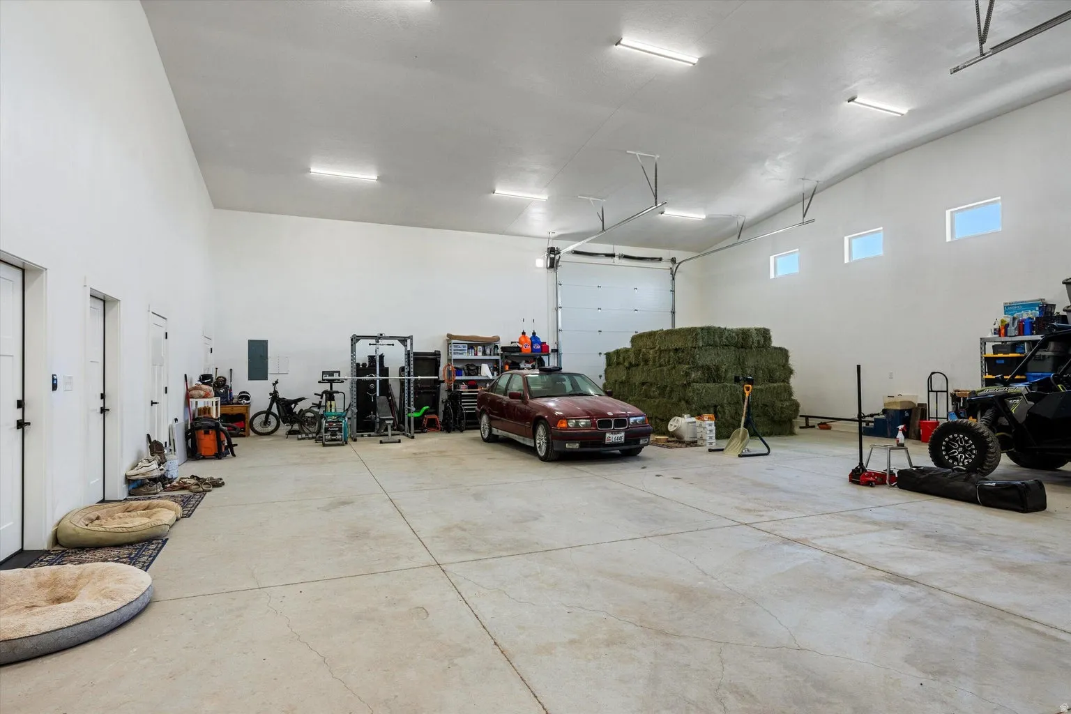Spacious interior garage featuring a high vaulted ceiling, multiple garage doors, concrete flooring, and transom windows
