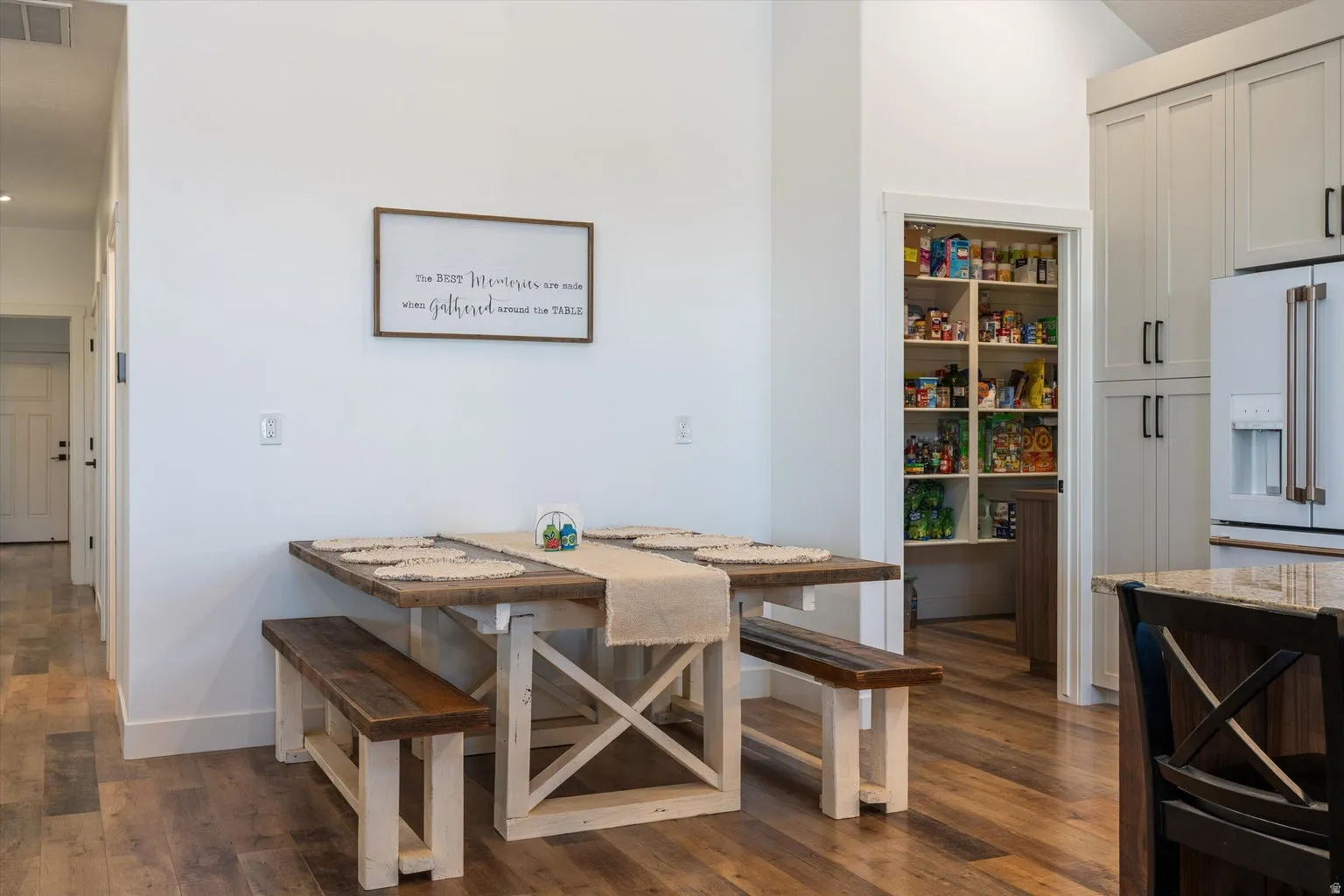 Kitchen dining area featuring wood-finish flooring, white walls, and a convenient walk-in pantry with ample shelving