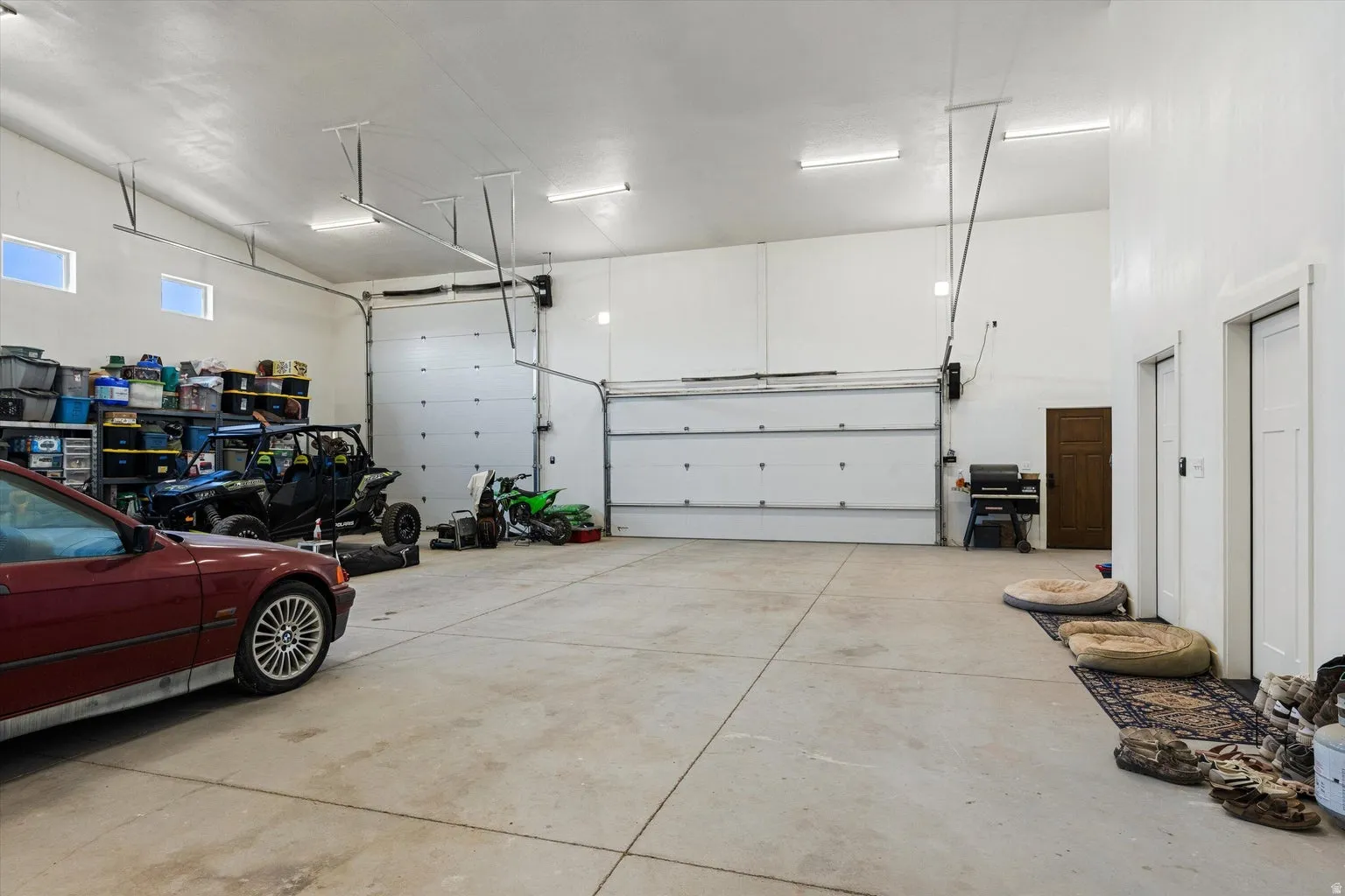 Expansive garage space featuring a vaulted ceiling and two large overhead doors