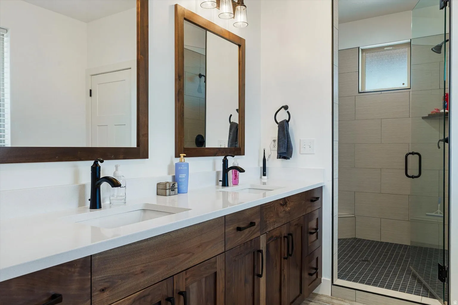 Double vanity with wood-finish cabinetry, white countertops, and undermount sinks
