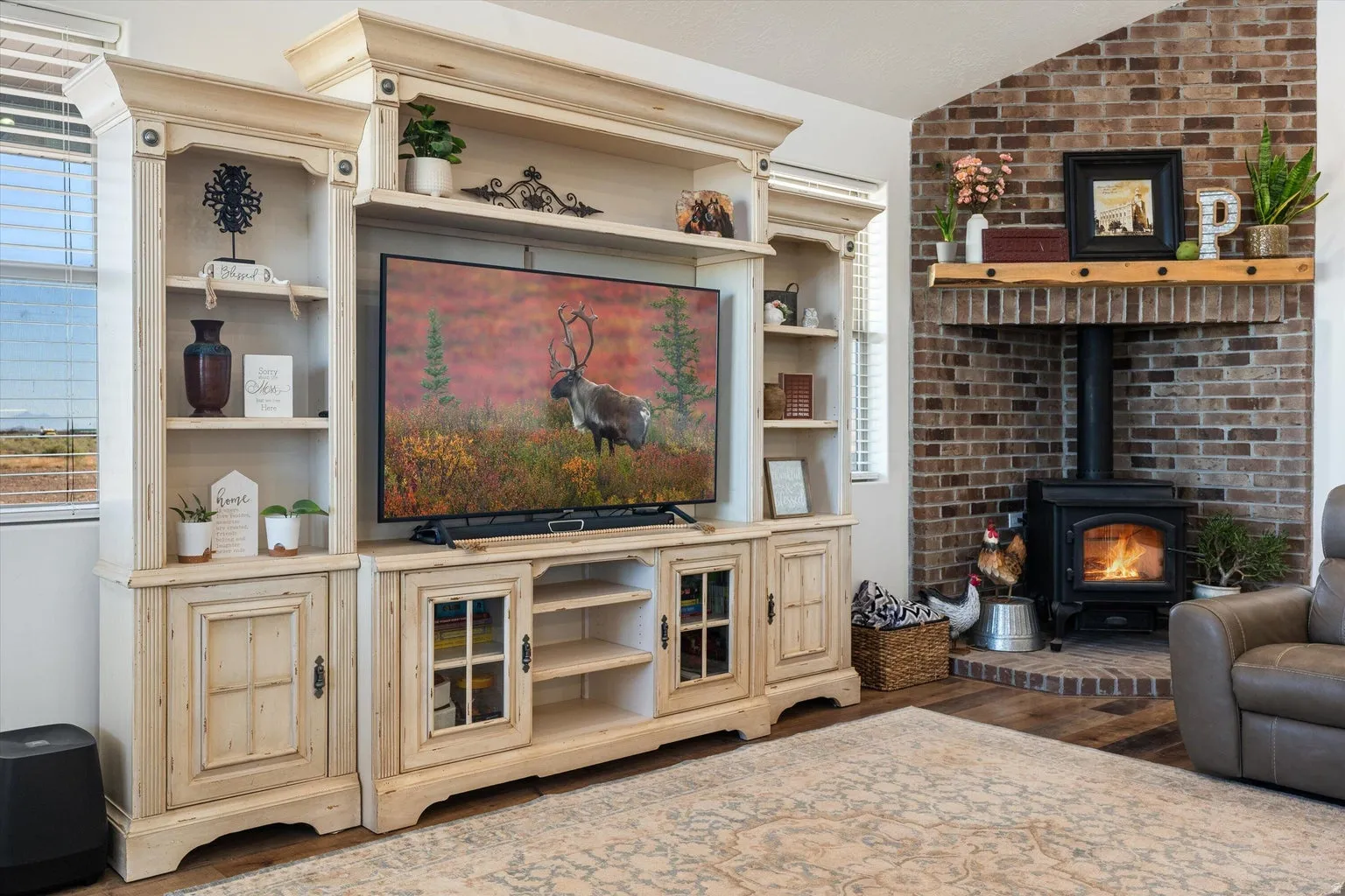 Living space featuring a built-in entertainment center, brick fireplace with a wood mantle, and a wood-burning stove