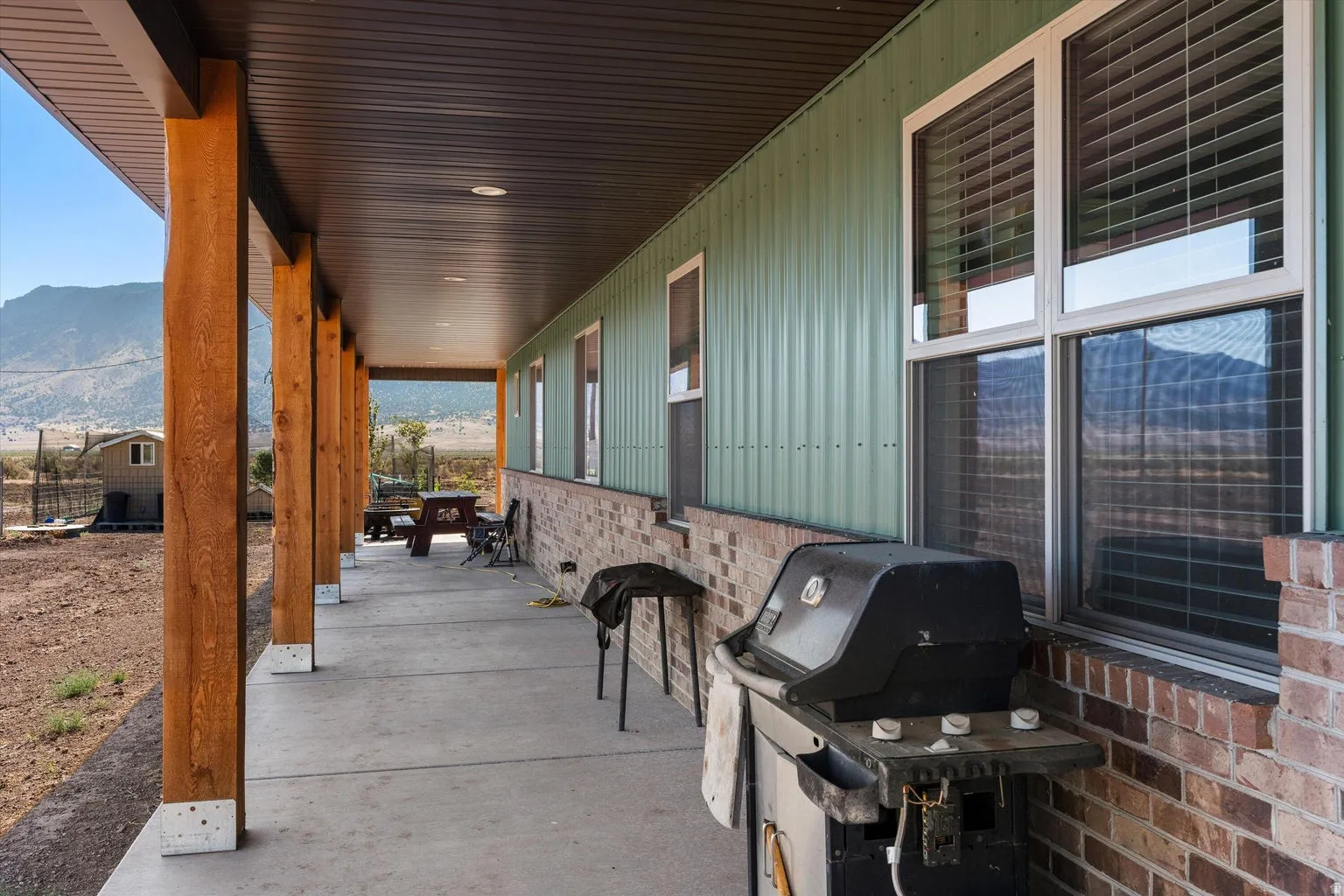Long covered patio featuring natural wood posts, a concrete surface, and a dark soffit with recessed lighting