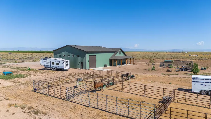 Expansive property featuring a large green barn structure with multiple windows and a covered porch with wooden columns