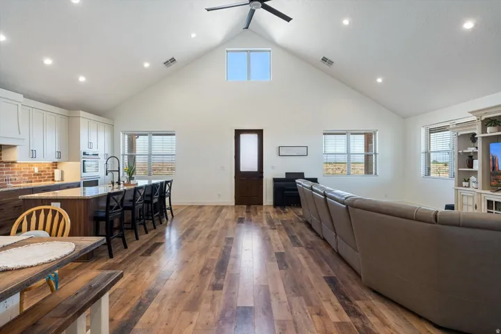 Open concept living area featuring wood-finish flooring, a vaulted ceiling with a ceiling fan, and recessed lighting