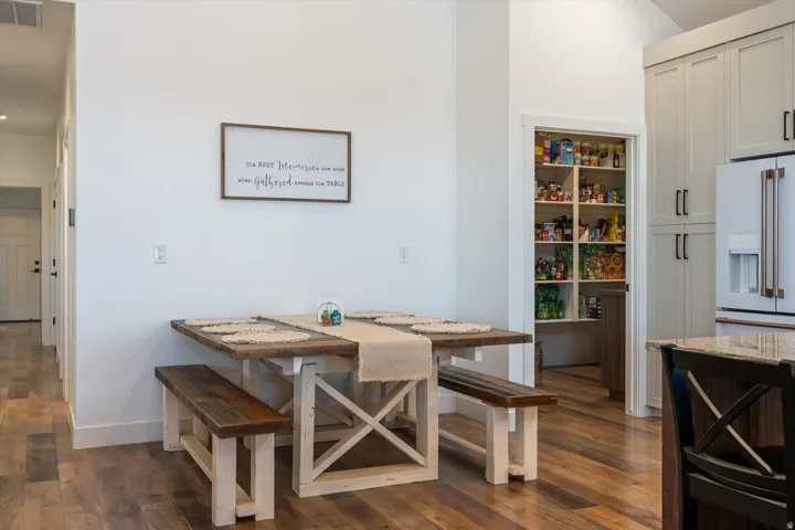 Kitchen dining area featuring wood-finish flooring, white walls, and a convenient walk-in pantry with ample shelving