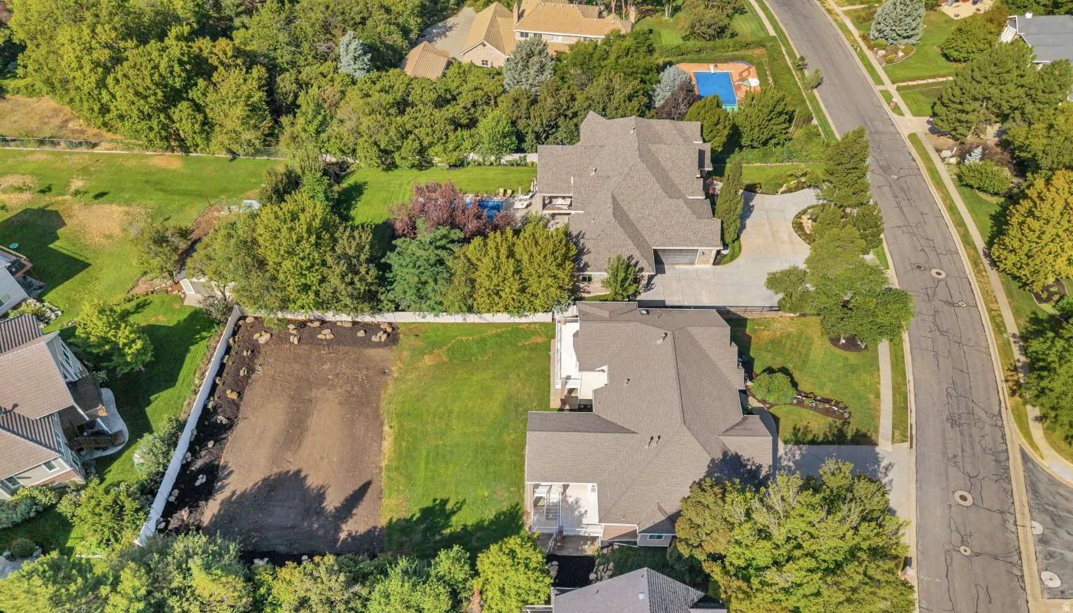 Expansive lot featuring a cleared building area, existing lawn space, and a white perimeter fence