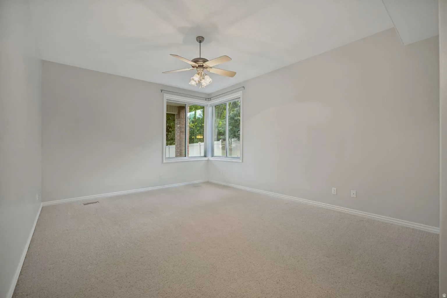 Vaulted ceiling with a ceiling fan, bay window, light neutral wall paint, and carpeting