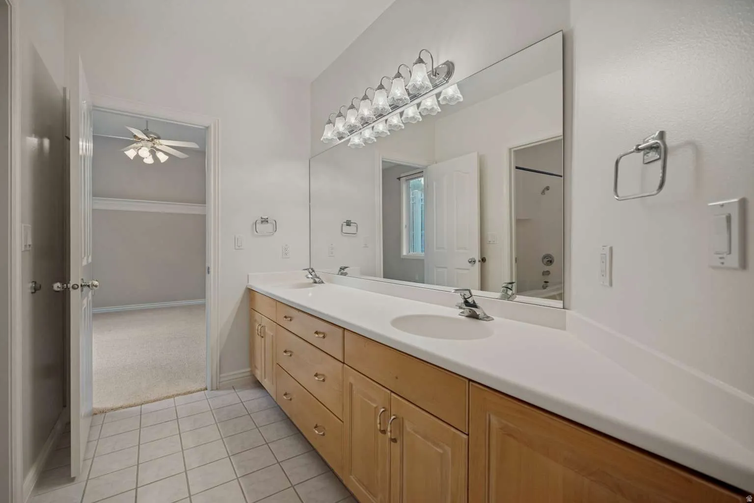 Dual vanity with light wood cabinetry, white countertops, and integrated sinks