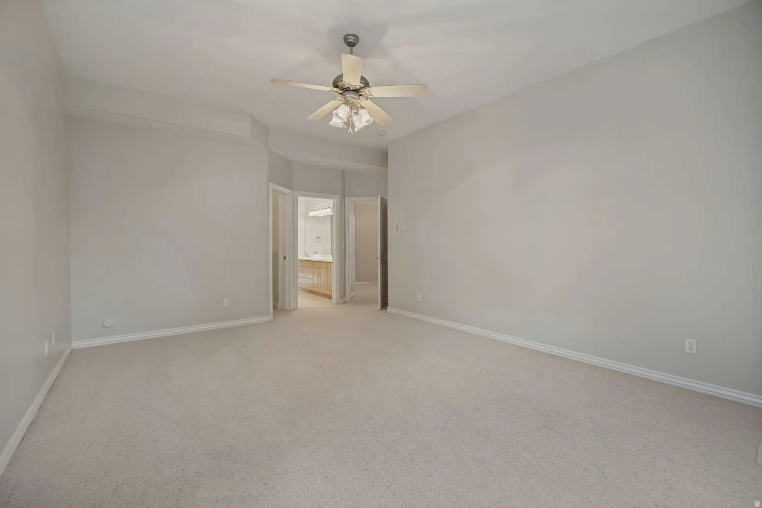 Spacious carpeted room featuring a ceiling fan with integrated lighting
