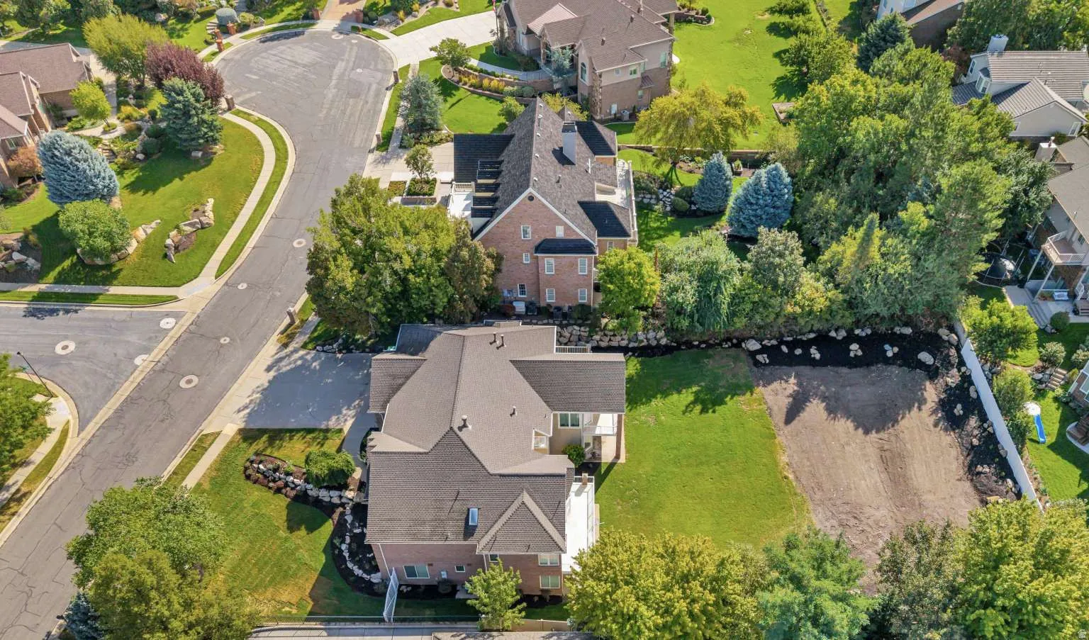 Expansive lot with partial landscaping and a white privacy fence
