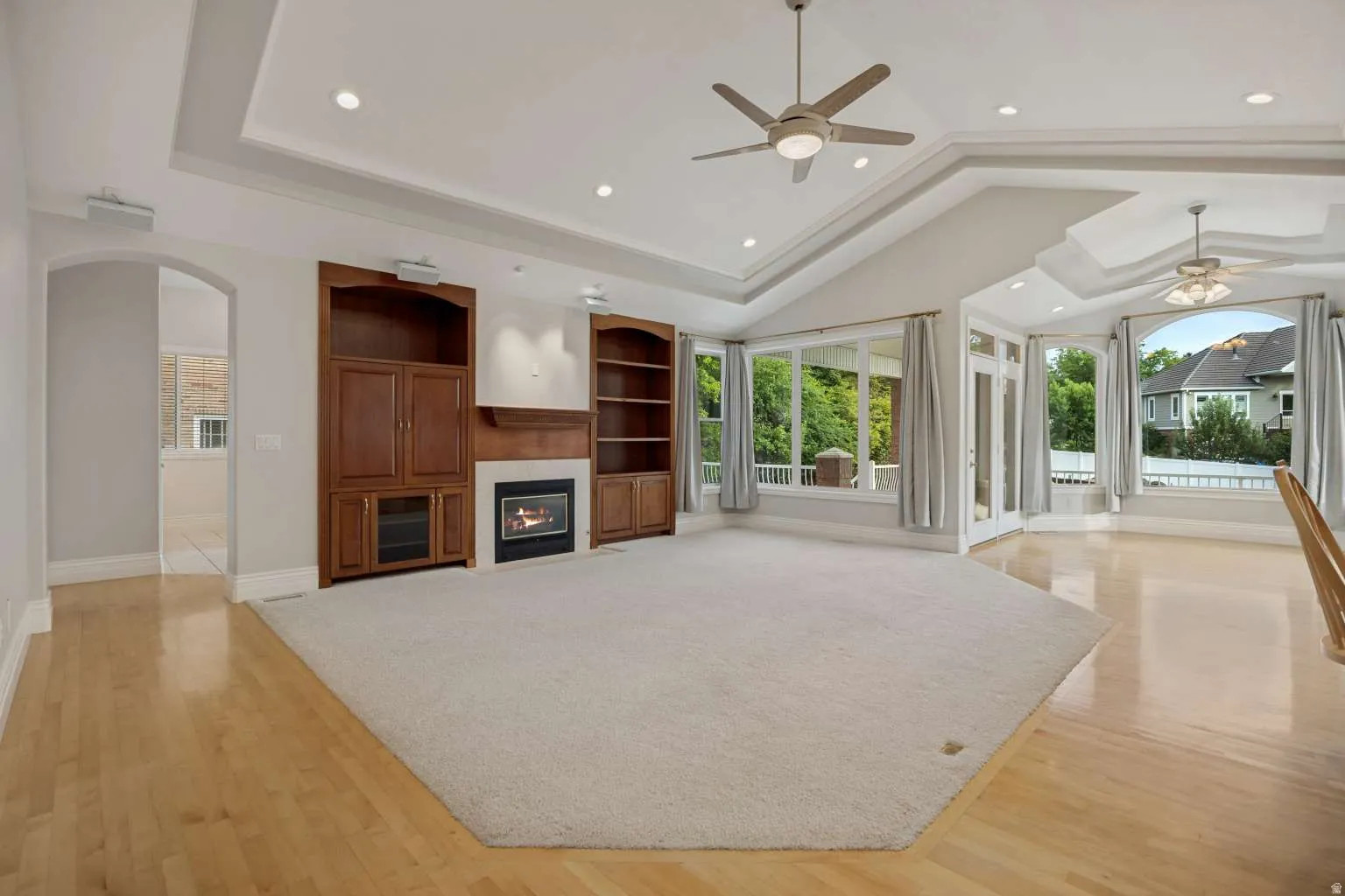 Spacious living area featuring a fireplace, built-in cabinetry, wood-finish flooring, recessed lighting, and expansive windows
