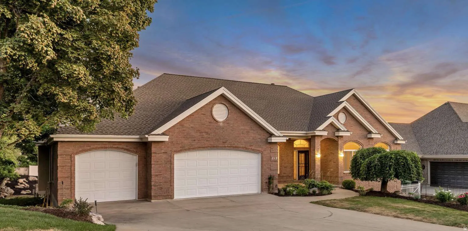 Brick exterior with arched garage doors, an arched entryway, and a concrete driveway