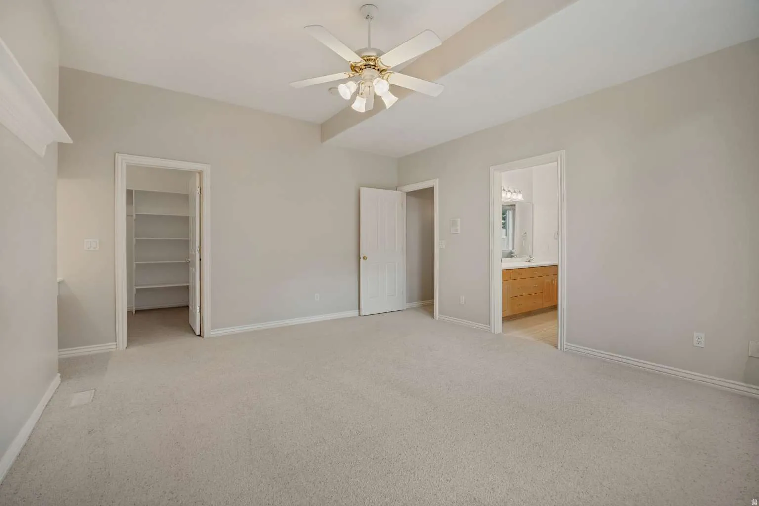 Vaulted ceiling with an attached ceiling fan, neutral carpeting, and a built-in closet system