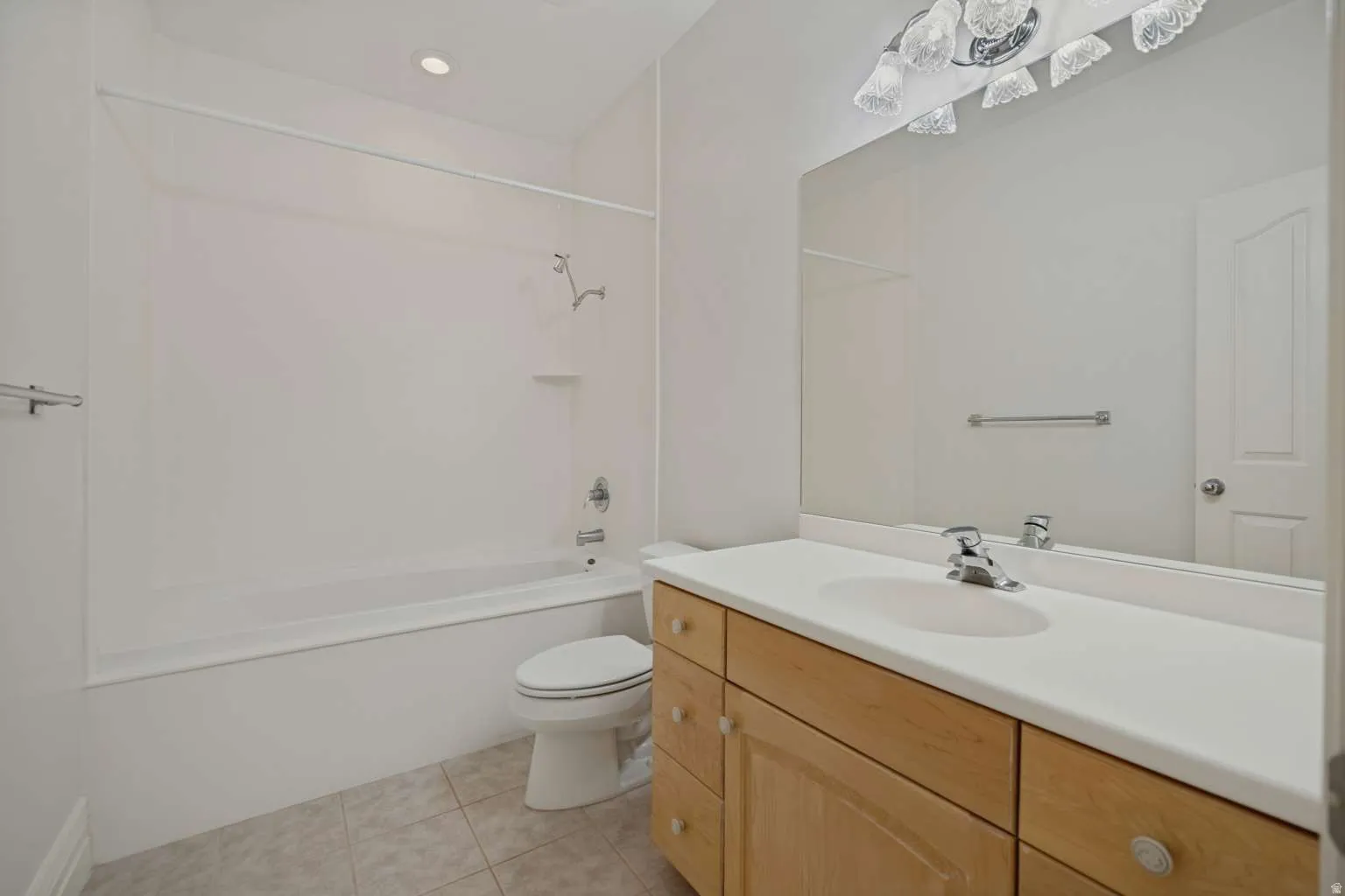 Bathtub and shower combination, single vanity with wood-finish cabinetry, integrated sink, and large wall-mounted mirror