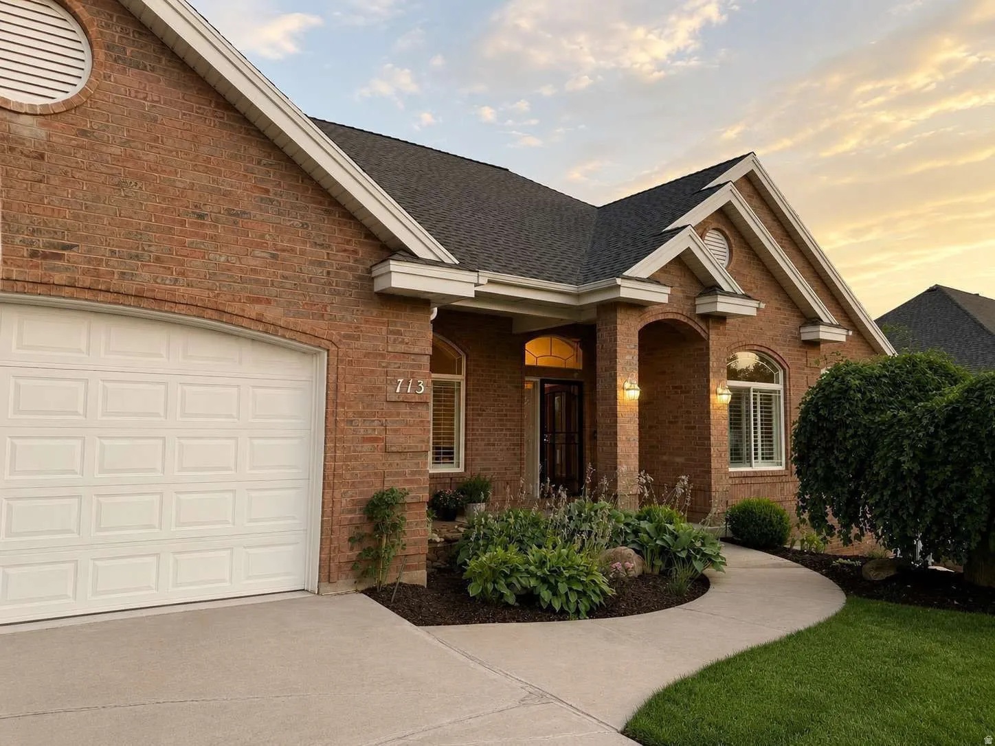 Brick exterior with white trim, arched entryways, and a curved concrete walkway