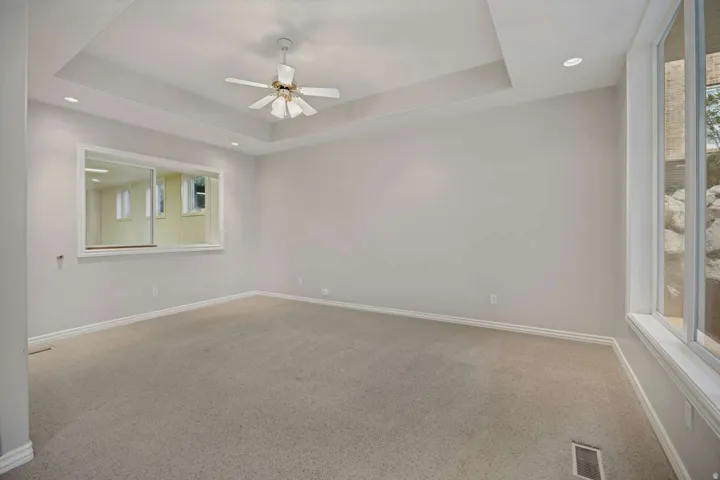 Tray ceiling with recessed lighting, ceiling fan, and carpeted flooring