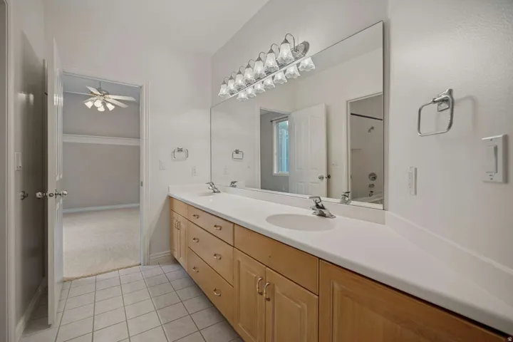Dual vanity with light wood cabinetry, white countertops, and integrated sinks