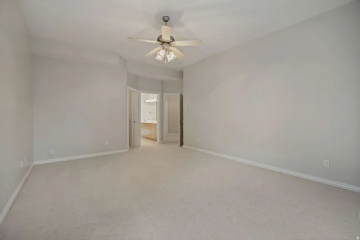 Spacious carpeted room featuring a ceiling fan with integrated lighting
