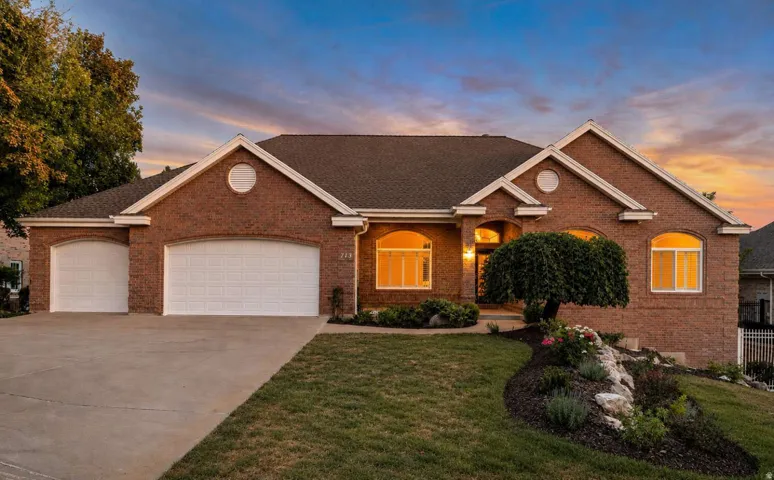 Brick exterior facade with arched windows, an attached two-car garage, and a concrete driveway