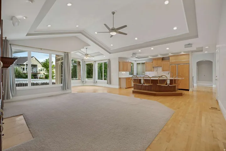 Expansive open-concept living area featuring a tray ceiling with recessed lighting and ceiling fans