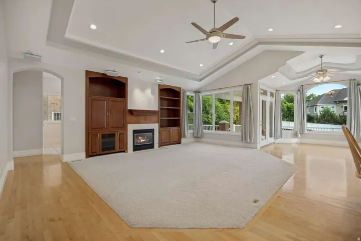 Spacious living area featuring a fireplace, built-in cabinetry, wood-finish flooring, recessed lighting, and expansive windows