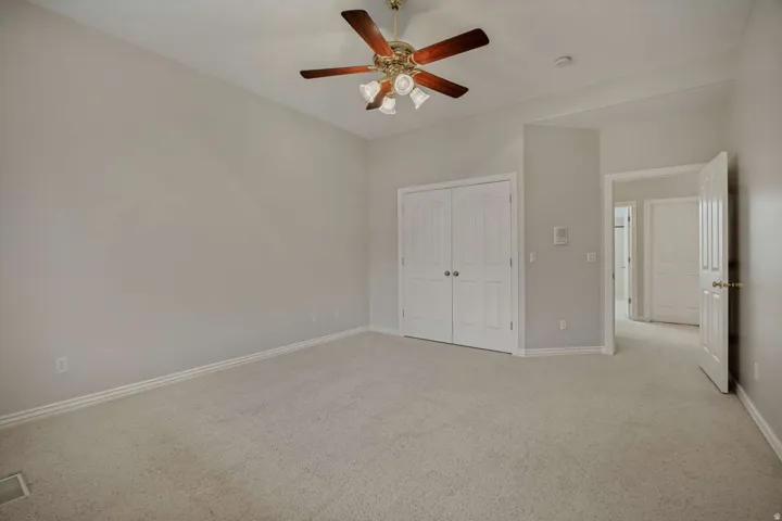Carpeted flooring, bi-fold closet doors, ceiling fan, and light wall finishes