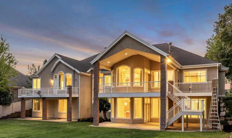 Multi-level stucco exterior with multiple balconies, brick pillars, and expansive windows